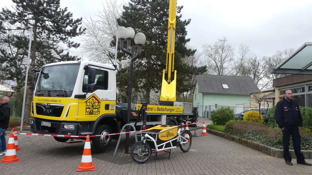 Lastwagen mit Kran und Lastenrad der Zimmerei vor der Halle